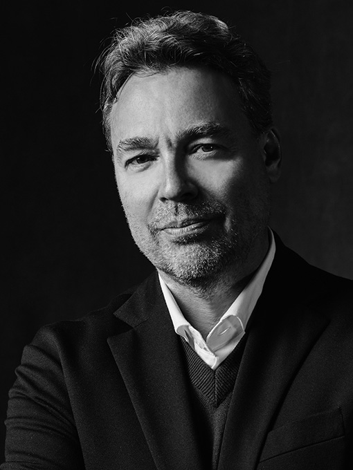 Portrait image of a man in a dark suit and white shirt.