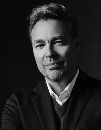 Portrait image of a man in a dark suit and white shirt.