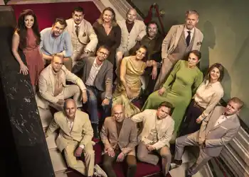 Several people are standing on a staircase, looking up at the camera.