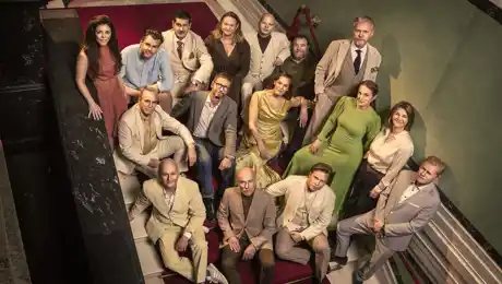 Several people are standing on a staircase, looking up at the camera.