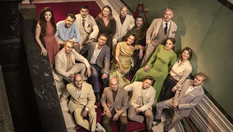 Several people are standing on a staircase, looking up at the camera.