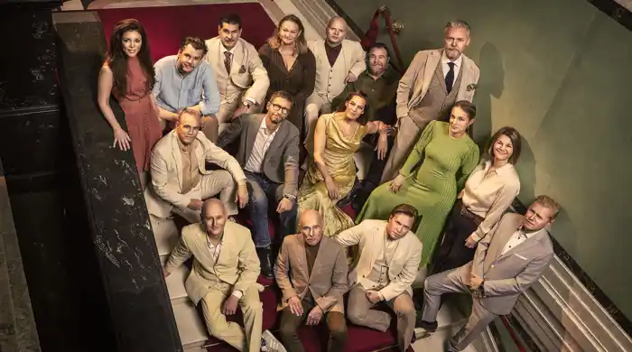 Several people are standing on a staircase, looking up at the camera.