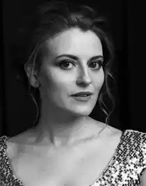 En närbild på en kvinna med uppsatt, lockigt hår, klädd i en topp med paljetter.