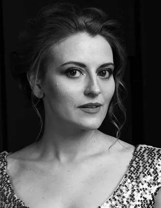 En närbild på en kvinna med uppsatt, lockigt hår, klädd i en topp med paljetter.