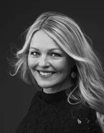 Närbild på blond kvinna med yvigt hår som ler mot kameran.