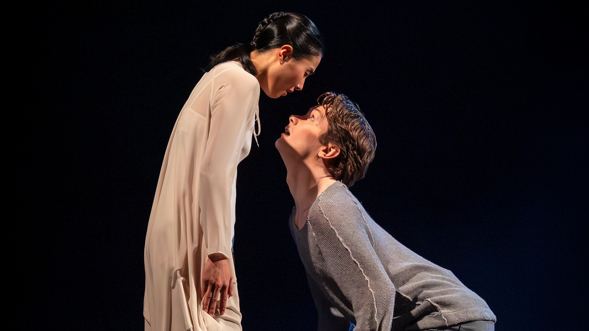 A couple of people that are standing on a dark stage.