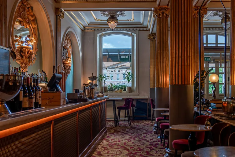 Ett rum med en lång bardisk till vänster och stolar och bord till höger.