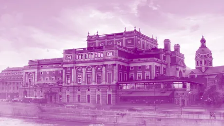 Ett stort hus vid ett vattendrag, en kyrka i bakgrunden, allt täckt av en lila färg.