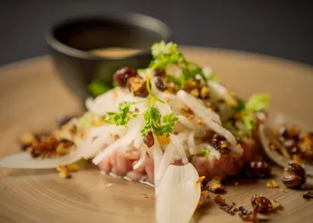 Närbild på mat, i bakgrunden en liten bägare med en sås.