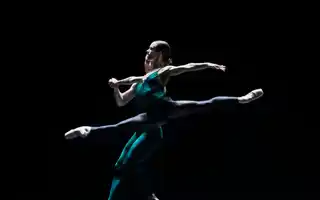 En manlig och en kvinnlig dansare dansar på en mörk scen.