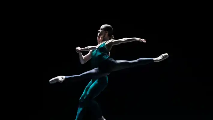 En manlig och en kvinnlig dansare dansar på en mörk scen.