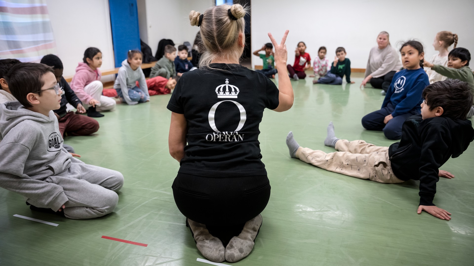 Unga Operan Operaworkshop  Barn som sitter i ring på ett golv.