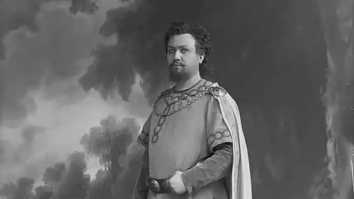 En man i historisk kostym står i vad som verkar vara en kuliss.